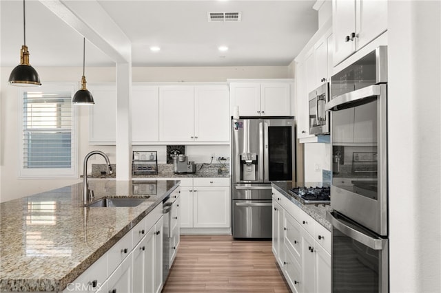 kitchen featuring stone counters, pendant lighting, sink, white cabinetry, and stainless steel appliances