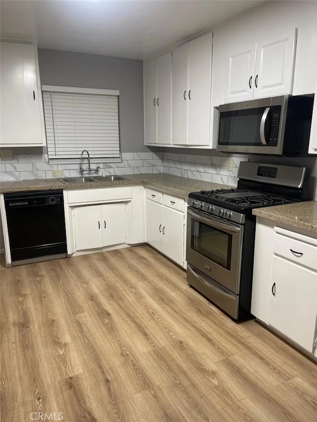 kitchen featuring white cabinetry, appliances with stainless steel finishes, decorative backsplash, light wood-type flooring, and sink