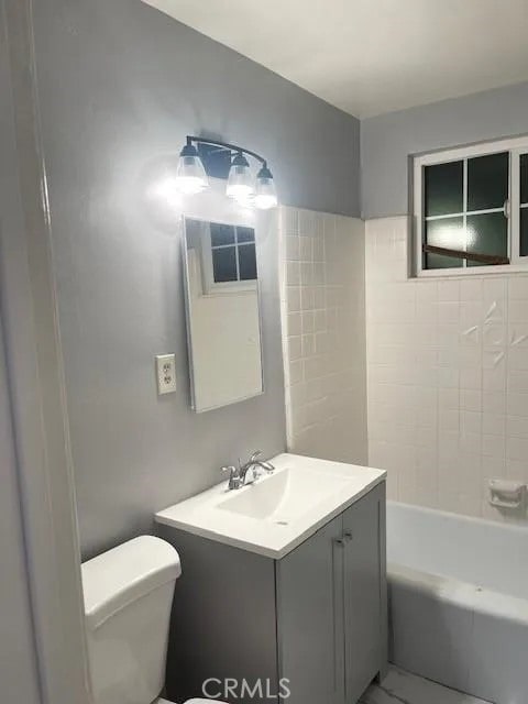 full bathroom with toilet, vanity, and tiled shower / bath combo