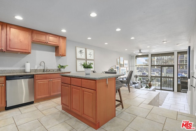 kitchen featuring stainless steel dishwasher, a center island, expansive windows, a kitchen breakfast bar, and sink