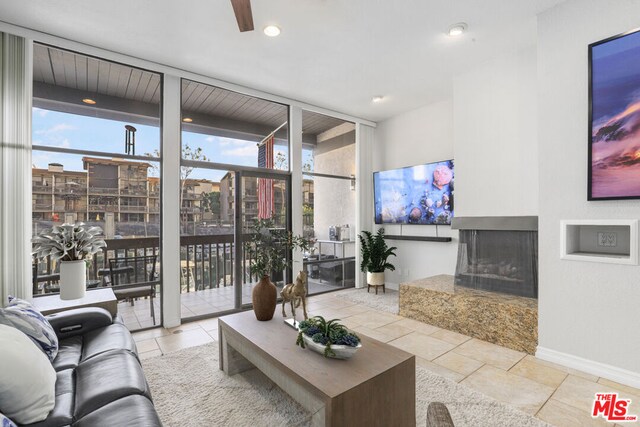 living room with a multi sided fireplace, light tile patterned flooring, and expansive windows