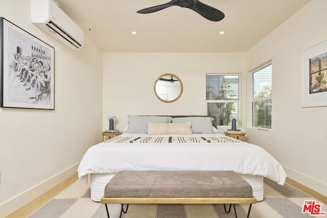 bedroom with a wall unit AC, ceiling fan, and light hardwood / wood-style floors