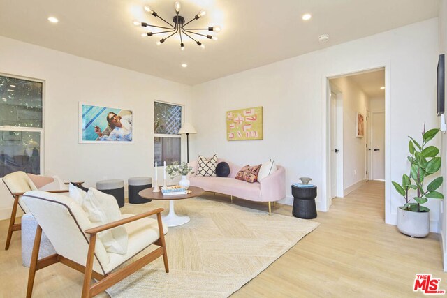 living room with light hardwood / wood-style floors and an inviting chandelier