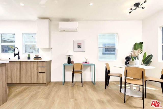 kitchen featuring light hardwood / wood-style flooring, plenty of natural light, an AC wall unit, and sink