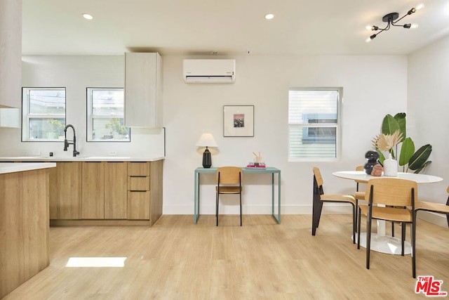 kitchen featuring light wood-type flooring, sink, and a wall mounted air conditioner