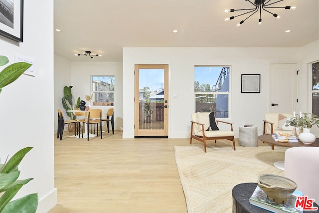 living room featuring light wood-type flooring, an inviting chandelier, and a wealth of natural light