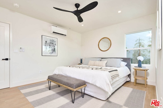 bedroom featuring a wall unit AC, ceiling fan, and light hardwood / wood-style flooring