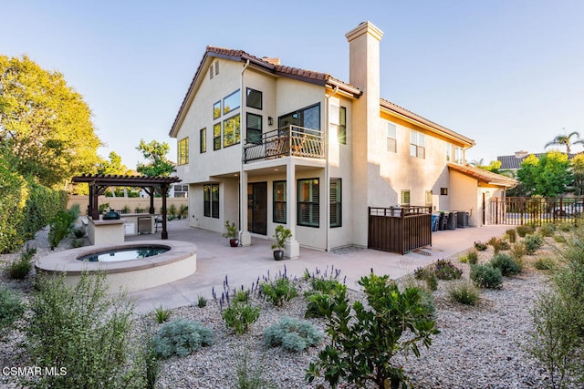 rear view of house featuring a balcony, exterior kitchen, a patio area, a pergola, and central air condition unit