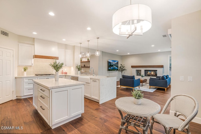 kitchen with decorative light fixtures, a center island, sink, custom range hood, and white cabinets