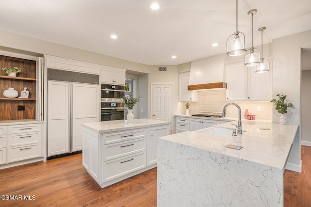 kitchen with hardwood / wood-style floors, paneled refrigerator, kitchen peninsula, and custom range hood