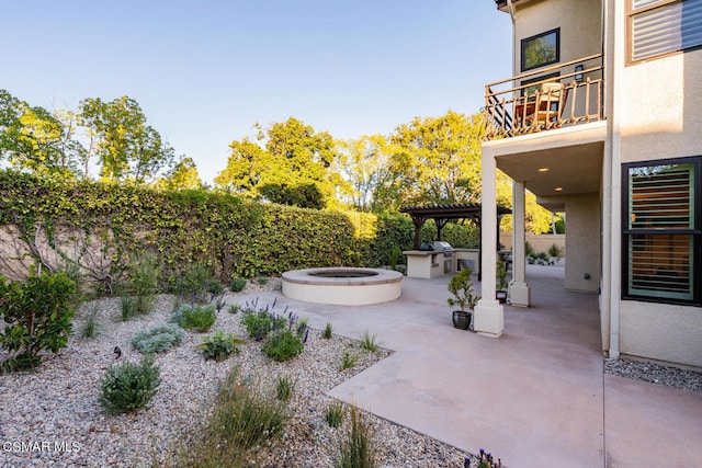 view of patio featuring a balcony, a grill, and exterior kitchen