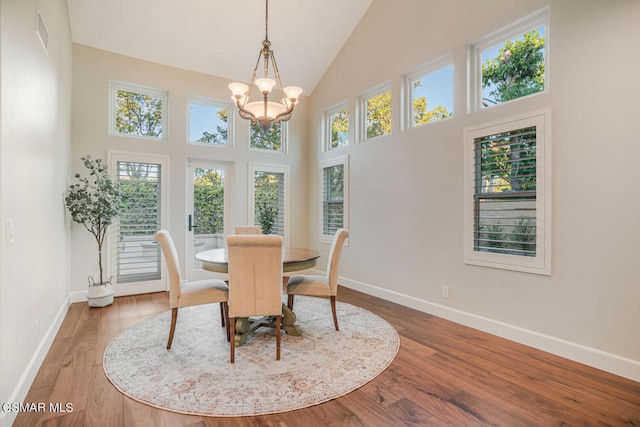 dining room with a wealth of natural light, a high ceiling, a chandelier, and hardwood / wood-style flooring