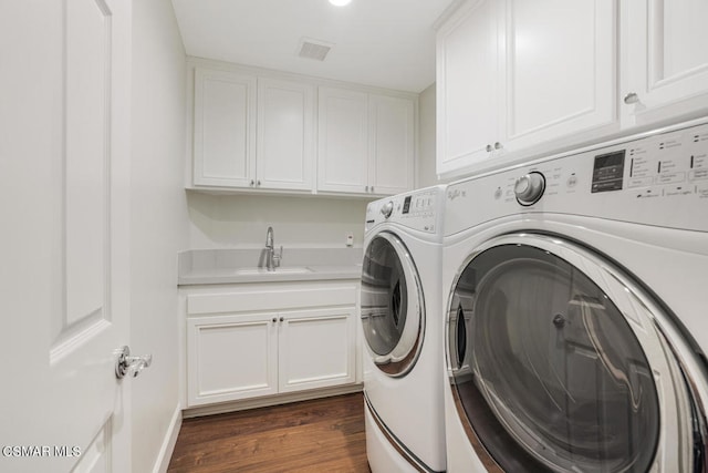 washroom with cabinets, sink, independent washer and dryer, and dark wood-type flooring