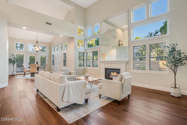 living room with a notable chandelier, a wealth of natural light, a high ceiling, and dark hardwood / wood-style floors