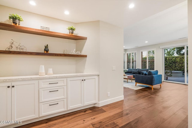 bar featuring white cabinets and light hardwood / wood-style flooring