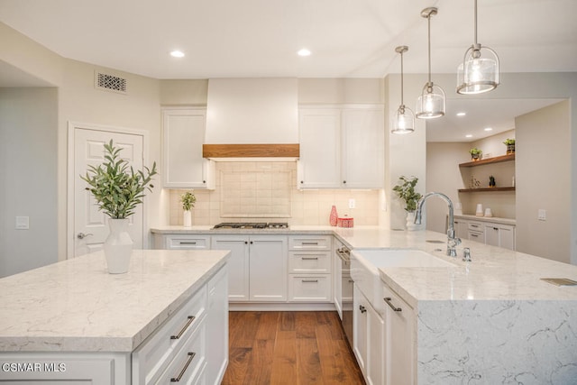 kitchen with decorative light fixtures, sink, white cabinets, and custom exhaust hood