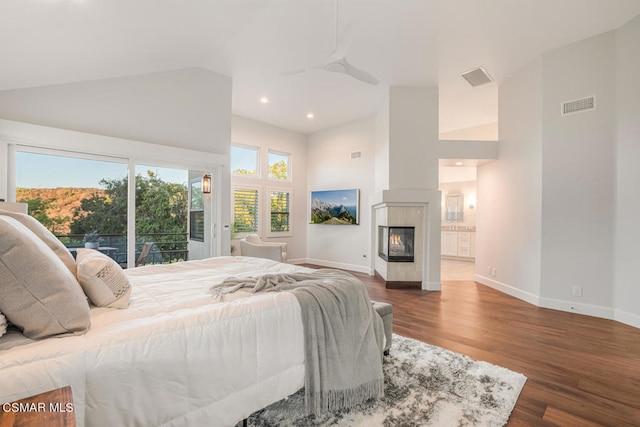 bedroom with ceiling fan, dark hardwood / wood-style floors, access to exterior, a multi sided fireplace, and multiple windows