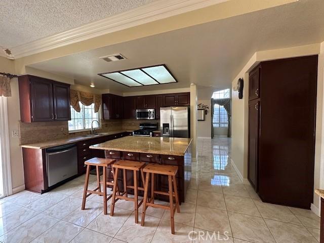 kitchen with stainless steel appliances, tasteful backsplash, light tile patterned flooring, a kitchen island, and a breakfast bar