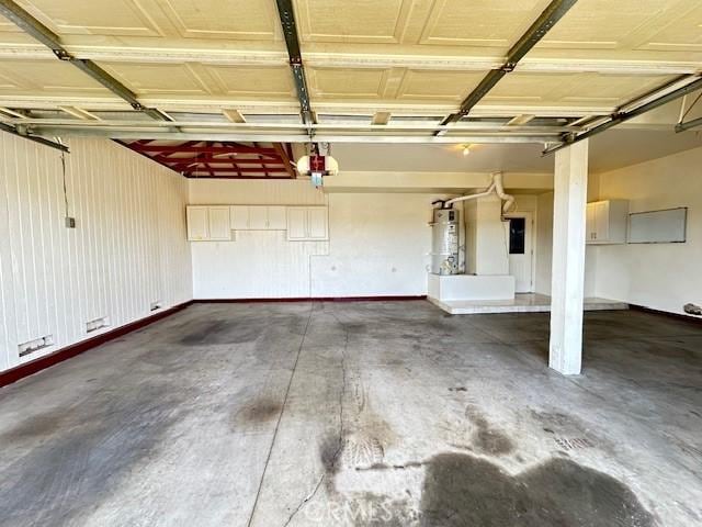 garage featuring a garage door opener, secured water heater, and electric panel