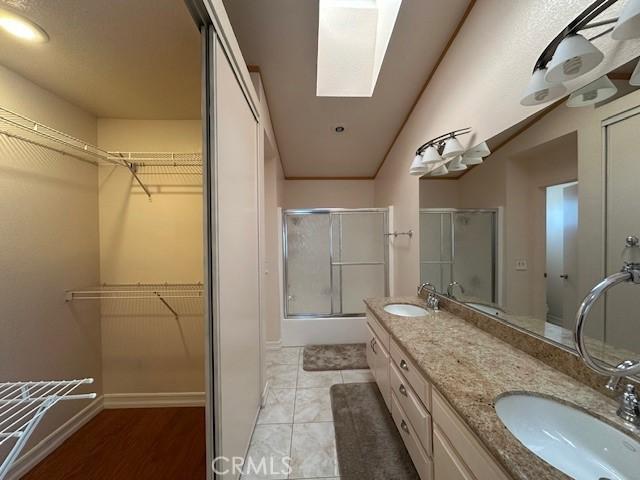 bathroom with a shower with door, a skylight, vanity, and tile patterned flooring