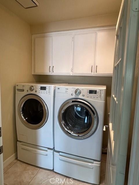 laundry room with light tile patterned flooring, washing machine and clothes dryer, and cabinets