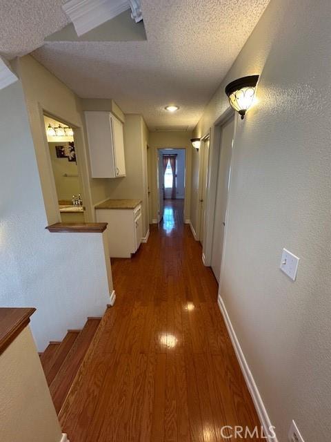 corridor with dark wood-type flooring and a textured ceiling