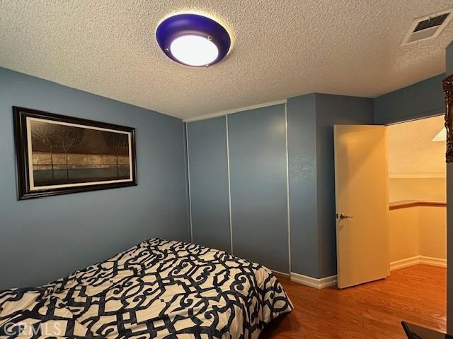 bedroom featuring wood-type flooring, a closet, and a textured ceiling