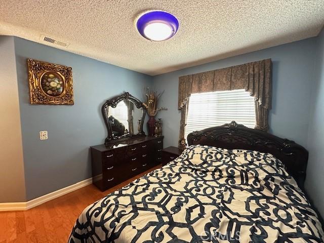 bedroom with a textured ceiling and dark hardwood / wood-style flooring