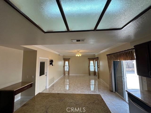 interior space featuring ceiling fan, light tile patterned floors, crown molding, and a textured ceiling