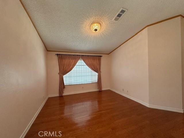 spare room with a textured ceiling, ornamental molding, and dark hardwood / wood-style floors