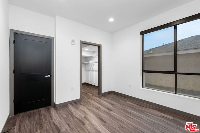 unfurnished bedroom with a walk in closet and hardwood / wood-style flooring