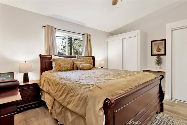 bedroom featuring ceiling fan, vaulted ceiling, a closet, and light wood-type flooring