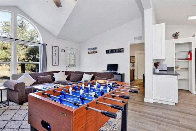 rec room with ceiling fan, vaulted ceiling, and light wood-type flooring