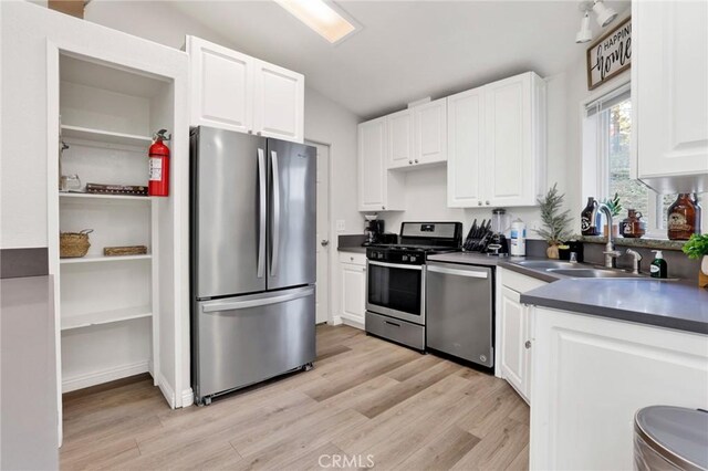 kitchen featuring appliances with stainless steel finishes, sink, white cabinetry, and light hardwood / wood-style floors