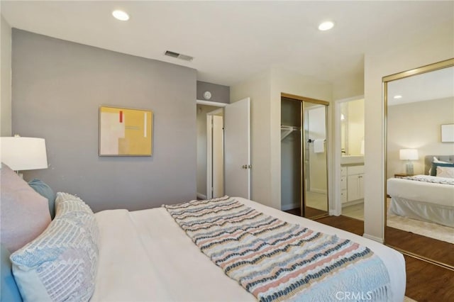 bedroom featuring connected bathroom and dark hardwood / wood-style flooring