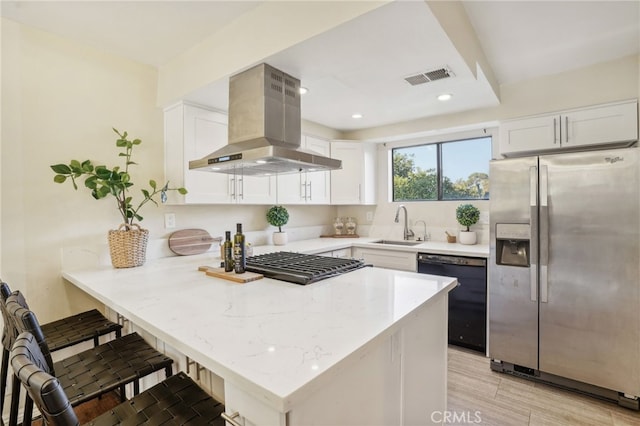 kitchen with a kitchen breakfast bar, stainless steel appliances, wall chimney exhaust hood, and kitchen peninsula