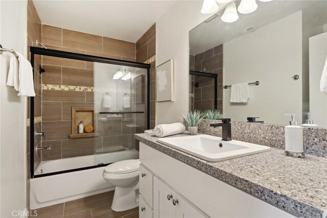 full bathroom with toilet, vanity, and combined bath / shower with glass door