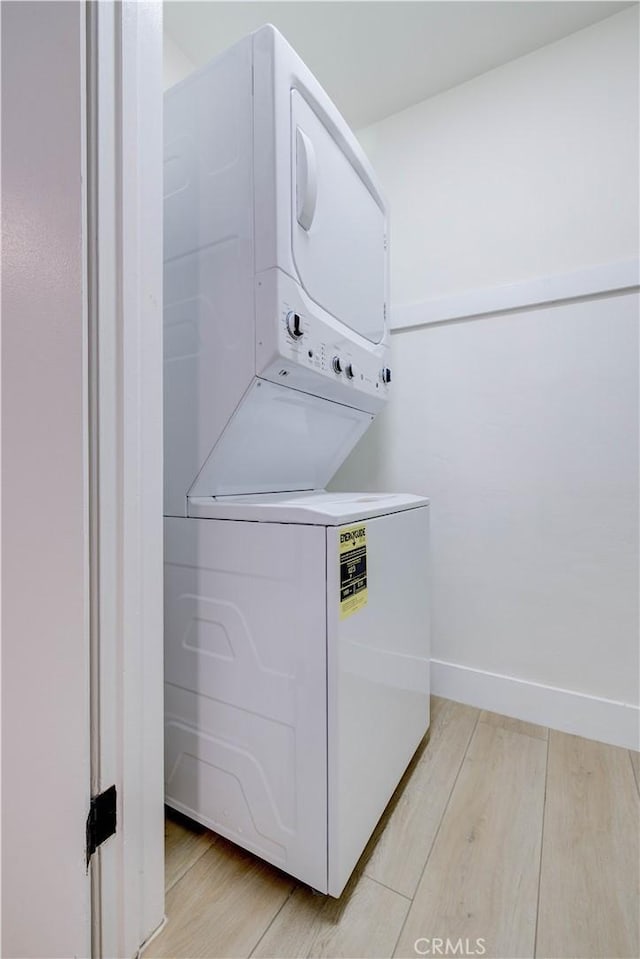 laundry room featuring stacked washer / dryer and light wood-type flooring