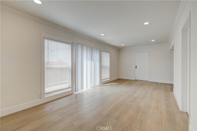 empty room featuring ornamental molding, a healthy amount of sunlight, and light hardwood / wood-style floors