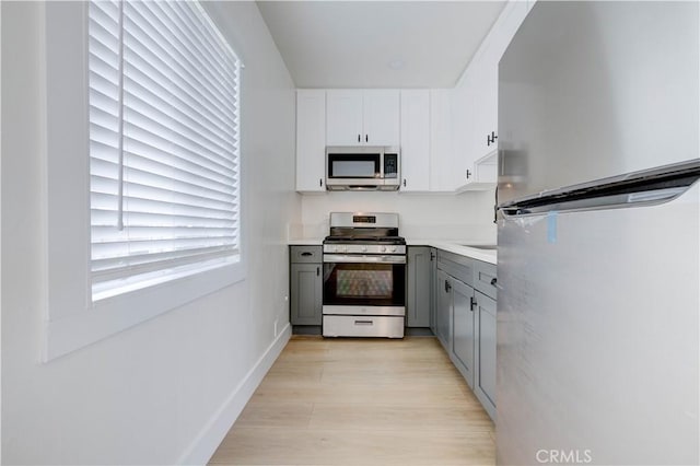 kitchen featuring light wood-type flooring, stainless steel appliances, white cabinetry, and gray cabinets