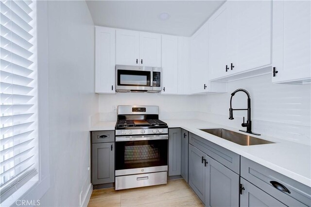 kitchen featuring sink, white cabinets, appliances with stainless steel finishes, and gray cabinets