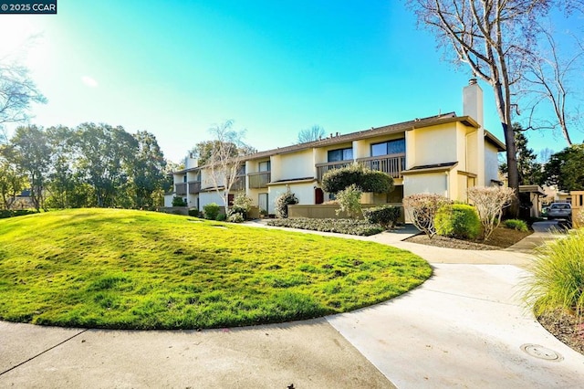 view of front of property with a balcony and a front yard