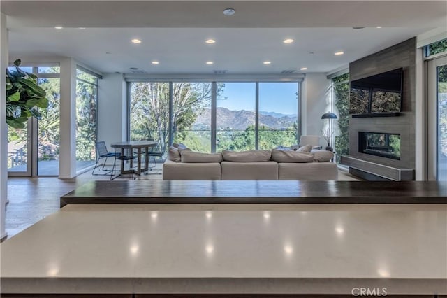 unfurnished living room featuring wood-type flooring, a wall of windows, and a tiled fireplace