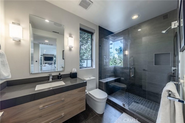 bathroom featuring toilet, vanity, tile patterned flooring, and a shower with shower door