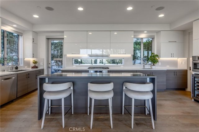 kitchen featuring appliances with stainless steel finishes, light hardwood / wood-style floors, white cabinets, and sink