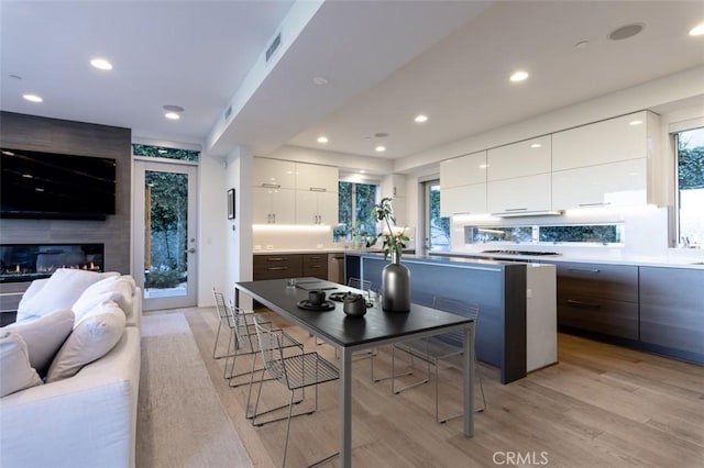 kitchen with a breakfast bar, white cabinetry, a center island with sink, and dark brown cabinets