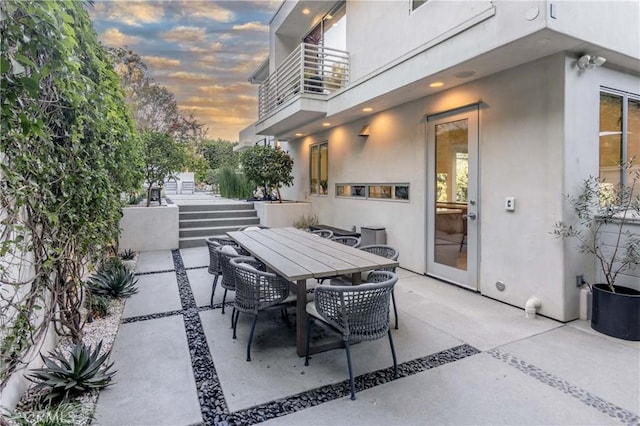 patio terrace at dusk featuring a balcony