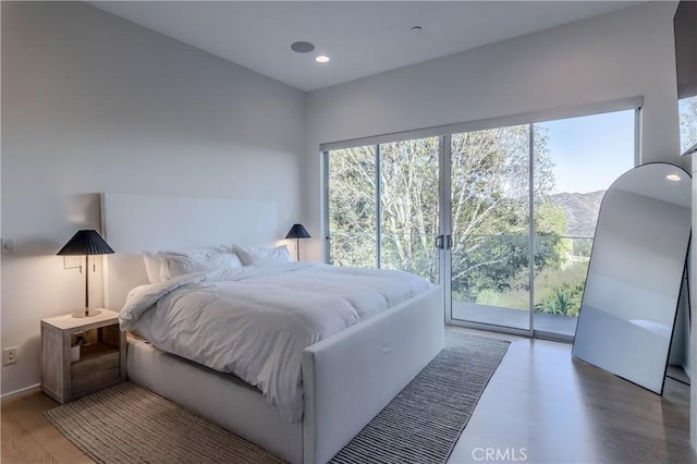 bedroom with access to exterior and hardwood / wood-style floors