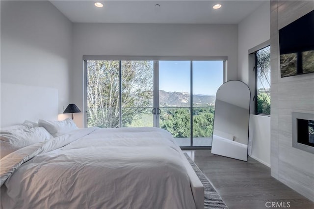 bedroom featuring dark wood-type flooring, a tile fireplace, and a mountain view