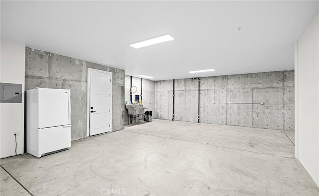 basement featuring sink, electric panel, and white refrigerator